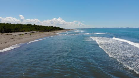 mare con onde bianche che si infrangono su una spiaggia di sabbia incontaminata in una giornata di sole sulla costa adriatica, veduta aerea