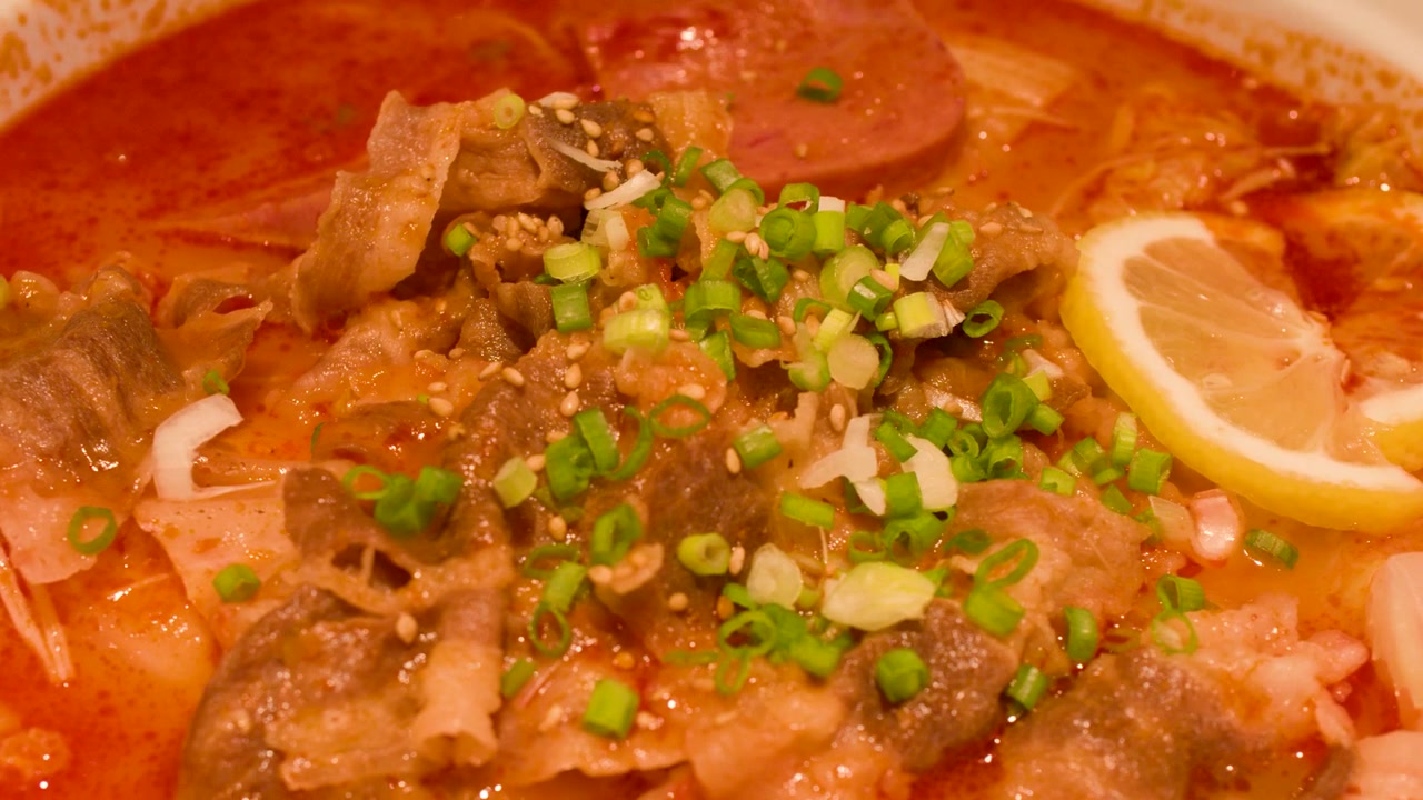 ภาพโคลสอัพนิ่งของบะหมี่หม้อไฟร้อนๆ ใส่เนื้อวัว ต้นหอม และมะนาวฝาน