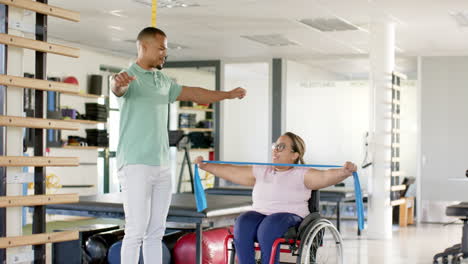 rehabilitation, therapist using resistance bands assisting woman with paraplegia in wheelchair