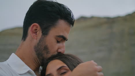 el novio amoroso abrazando a la chica por la noche en las montañas. el hombre besando a la esposa verticalmente