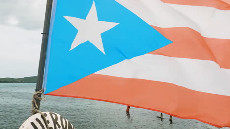 Dolly-forward-shot-along-jetty-overlooking-sea-rising-up-to-a-flag-of-Puerto-Rico