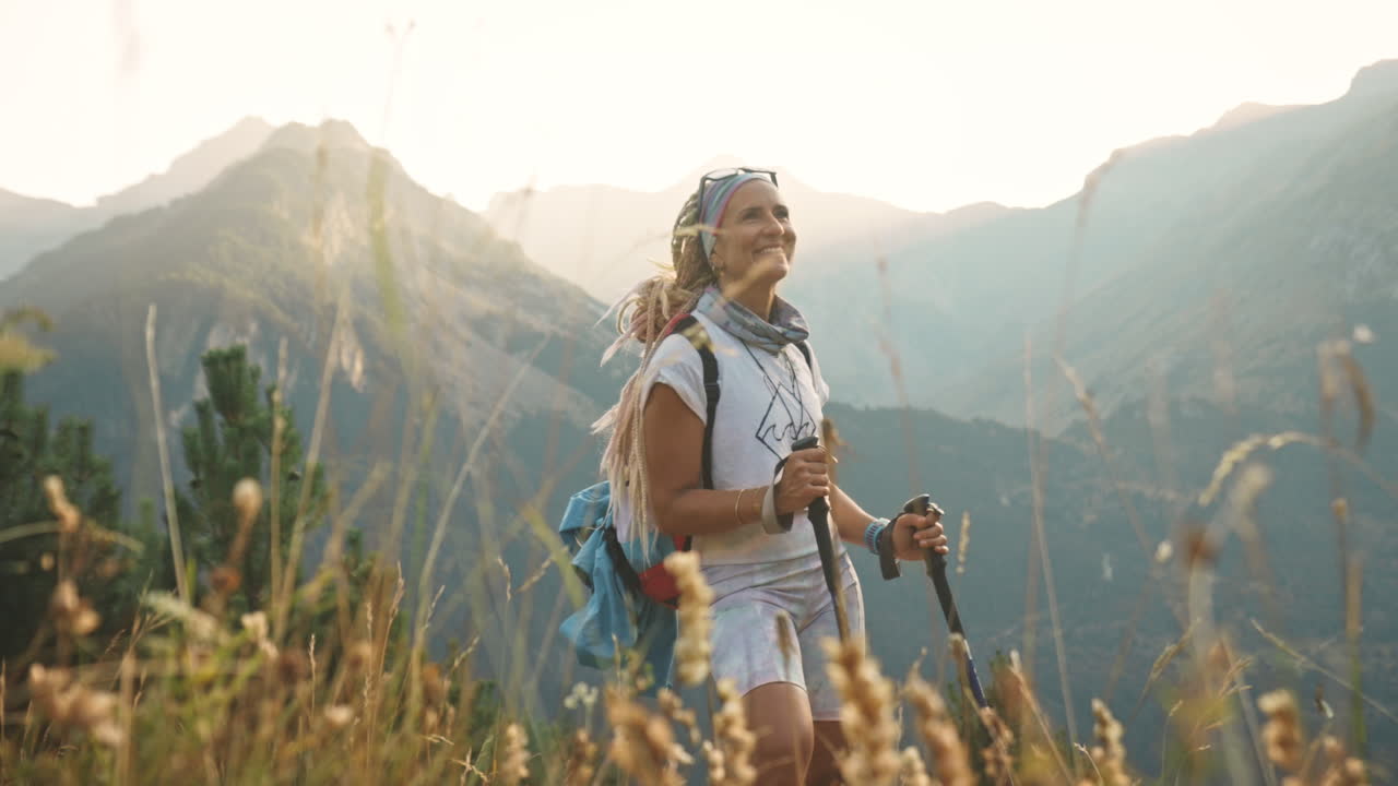 mujer rubia con rastas haciendo senderismo al atardecer sonríe, benasque, españa, plano medio
