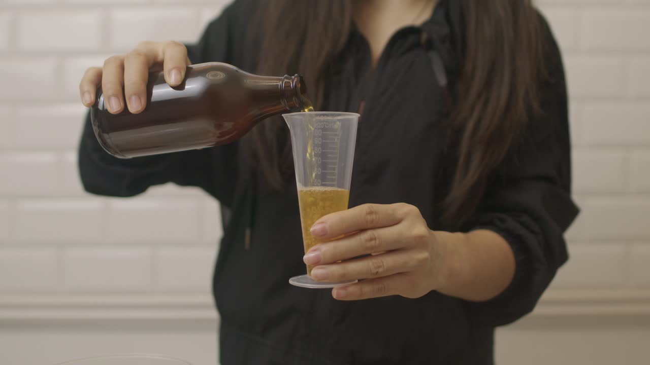 mujer pone líquido de cultivo de bacterias dentro de vidrio de medida