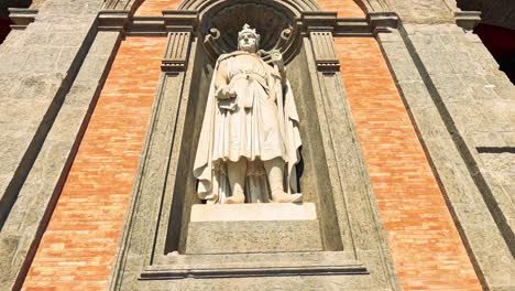 a statue emerges from a brick facade