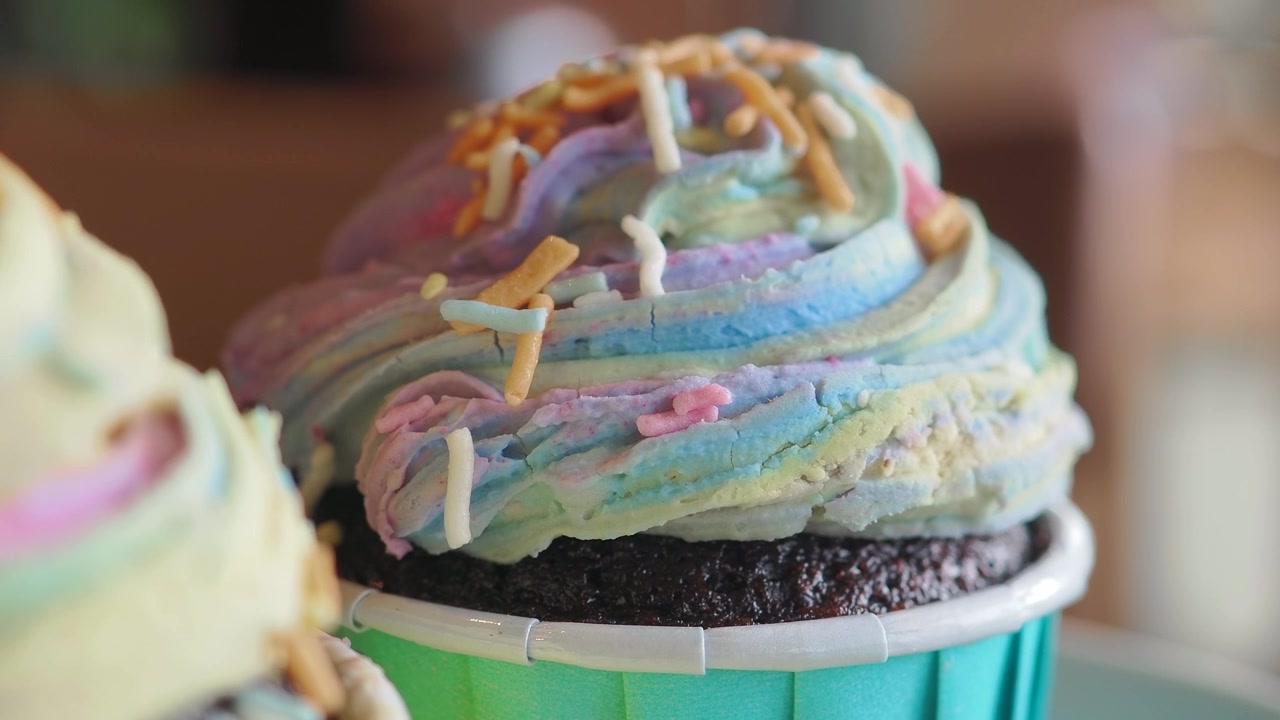 Primo piano di un delizioso cupcake al cioccolato con glassa a spirale color pastello