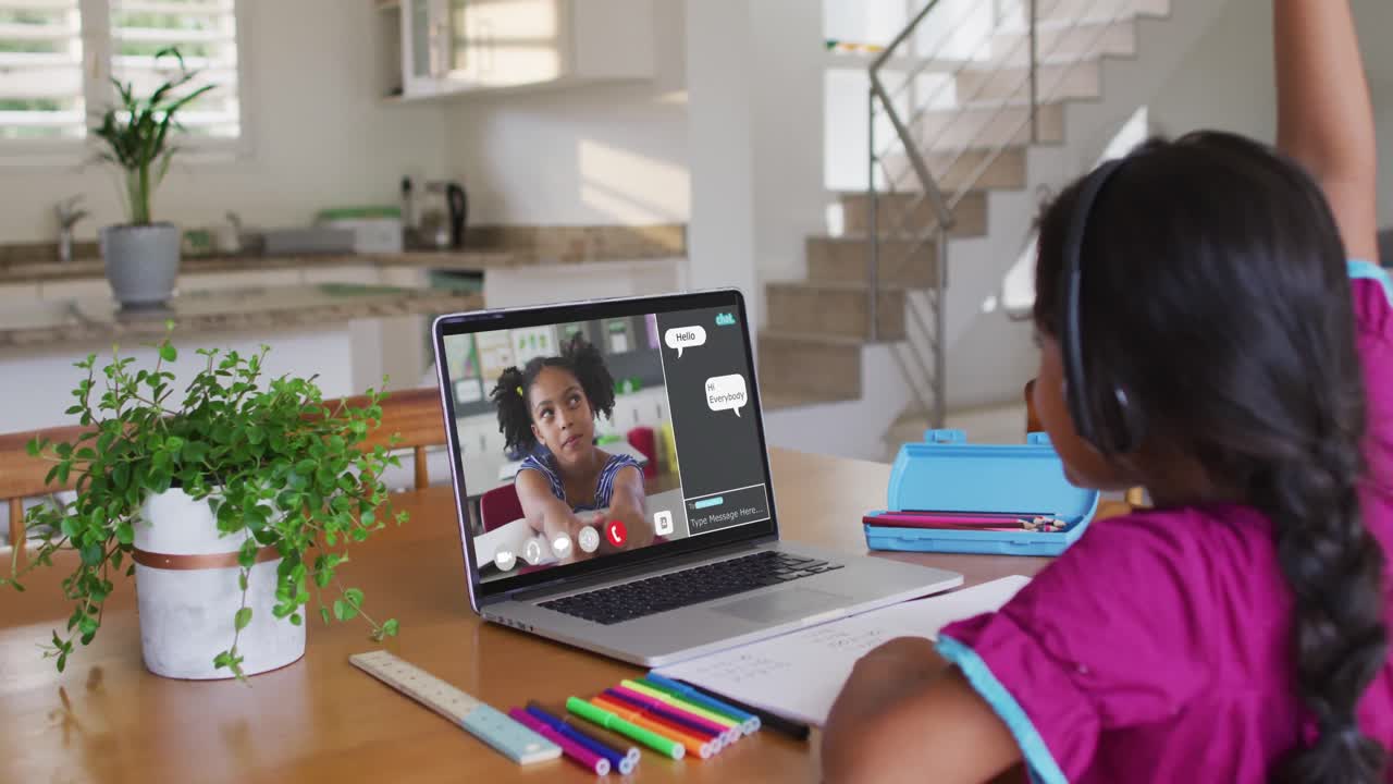 Schoolgirl using laptop for online lesson at home, with her colleague and web chat on screen