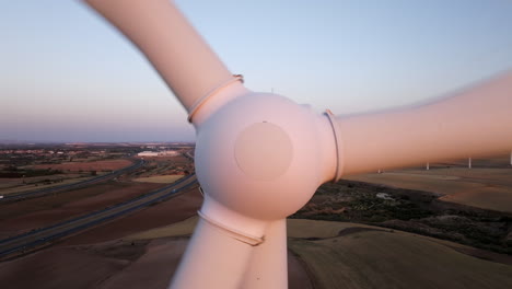 close-up view of wind turbine hub with wind farm in background