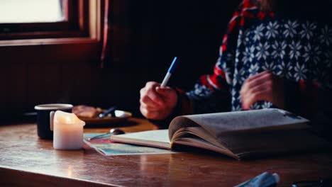 a man flips through the pages of a journal before writing in it, inside a cozy cabin in reinsjøen in åfjord, trøndelag, norway - close up