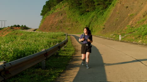 slow-motion-solo-female-woman-trekking-with-backpack-on-mountains-road-in-rural-countryside