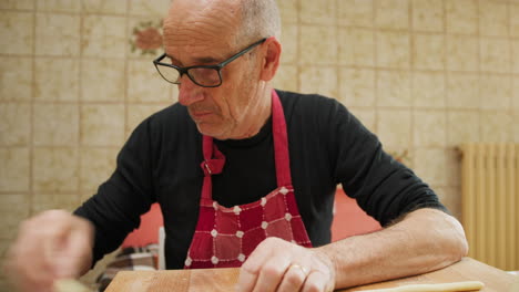 elderly man works raw dough in the morning in the kitchen