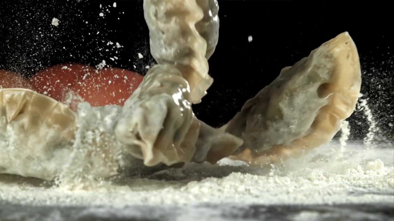 Raw Dumplings Falling onto Flour with Eggs in Slow Motion