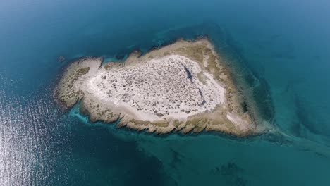 isolated desert island in the middle of a blue calm sea through sunshine morning