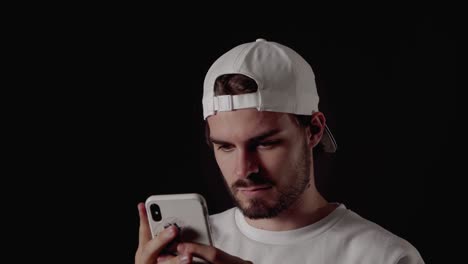 trendy 20s man using his mobile phone, close, black background