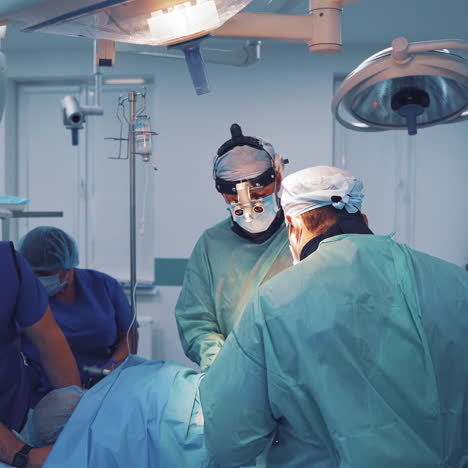 camera moves into the operating room close to the group of surgeons in clinic. doctors and assistants perform an operation on the background of a modern equipment in hospital.