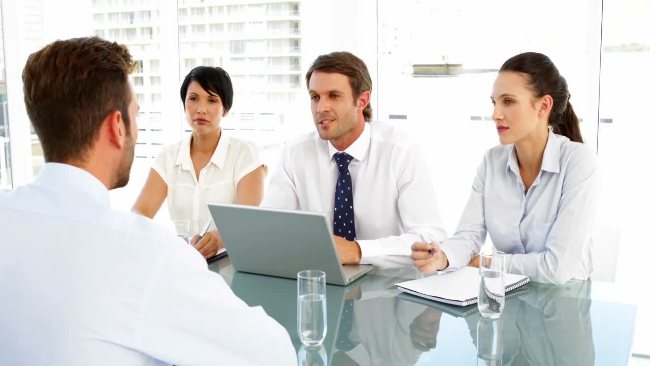 미소 짓는 면접 위원회 가 지원자 와 대화 하고 있다