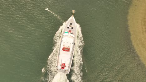 Eine-Aufnahme-Von-Oben-Nach-Unten-Direkt-über-Einem-Fischerboot,-Das-An-Einem-Bewölkten-Morgen-Aufs-Meer-Hinausfährt