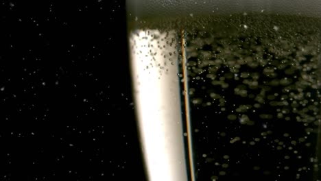 Animation-of-confetti-falling-and-bubbles-rising-in-glass-of-champagne-on-black-background