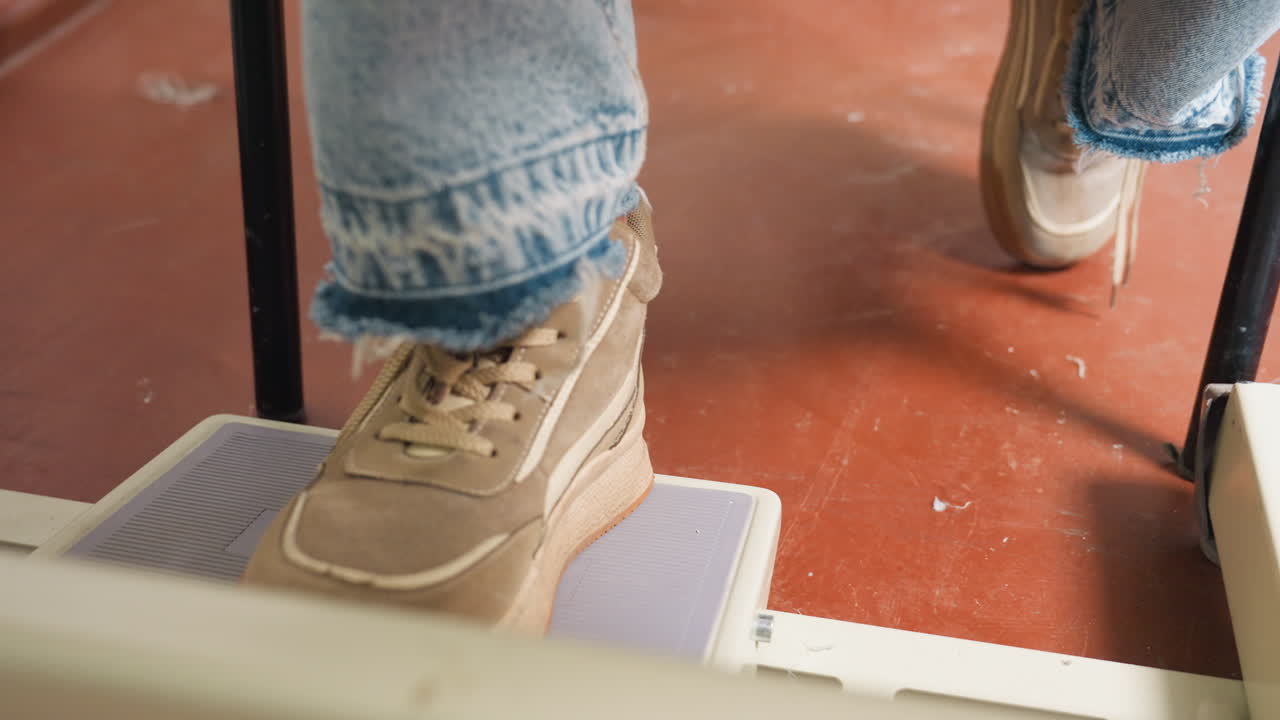 Designer wearing jeans and sports shoe, foot on pedal controlling machine speed, ensuring precision, stable posture, maintaining smooth pace, skillful operation for effective garment production