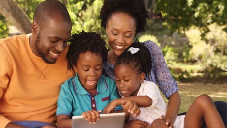 Die-Familie-Sitzt-Im-Gras-Und-Schaut-Auf-Ein-Tablet