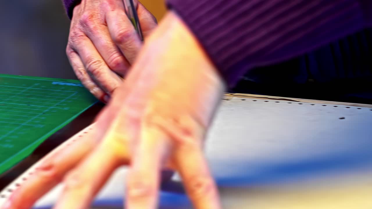 Craftsman cutting material on table, precise work, focus on hands