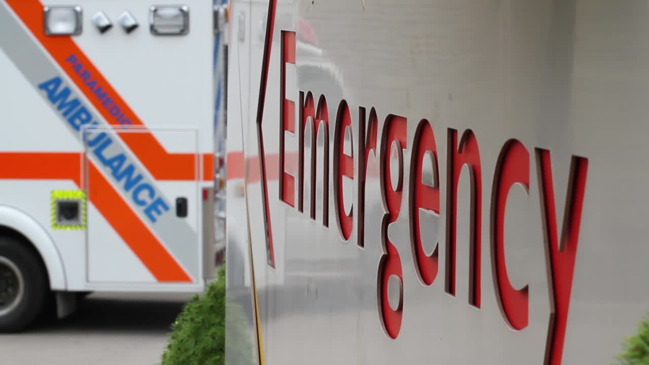 Hospital Emergency sign with ambulance in background.