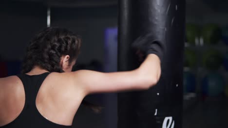 mujer joven con guantes de boxeo entrenando con un saco de boxeo en un club de boxeo. disparo en cámara lenta