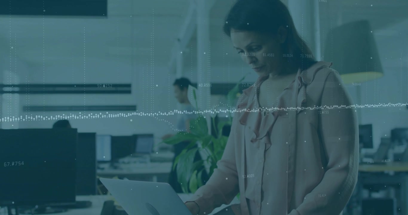 Adult woman approaching desk lifting laptop reviewing business data with animated waveform overlay