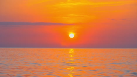 calm sea with sunset sky and sun through clouds overhead