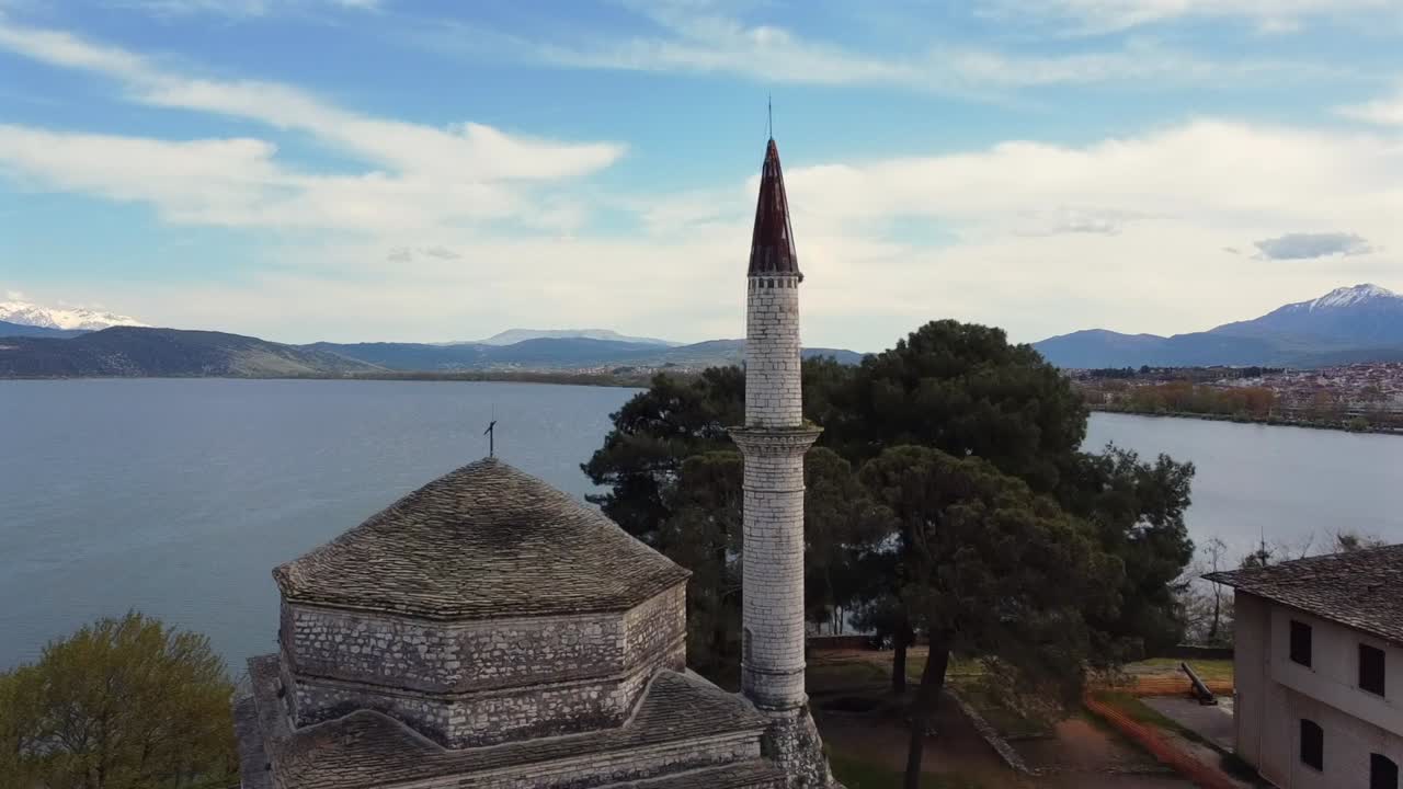 Nagranie z drona powoli przelatującego nad historycznym Meczetem Fethiye i żeliwnym, kratowanym grobowcem Alego Paszy w cytadeli Its Kale Zamku Ioannina z Jeziorem Pamvotida w tle