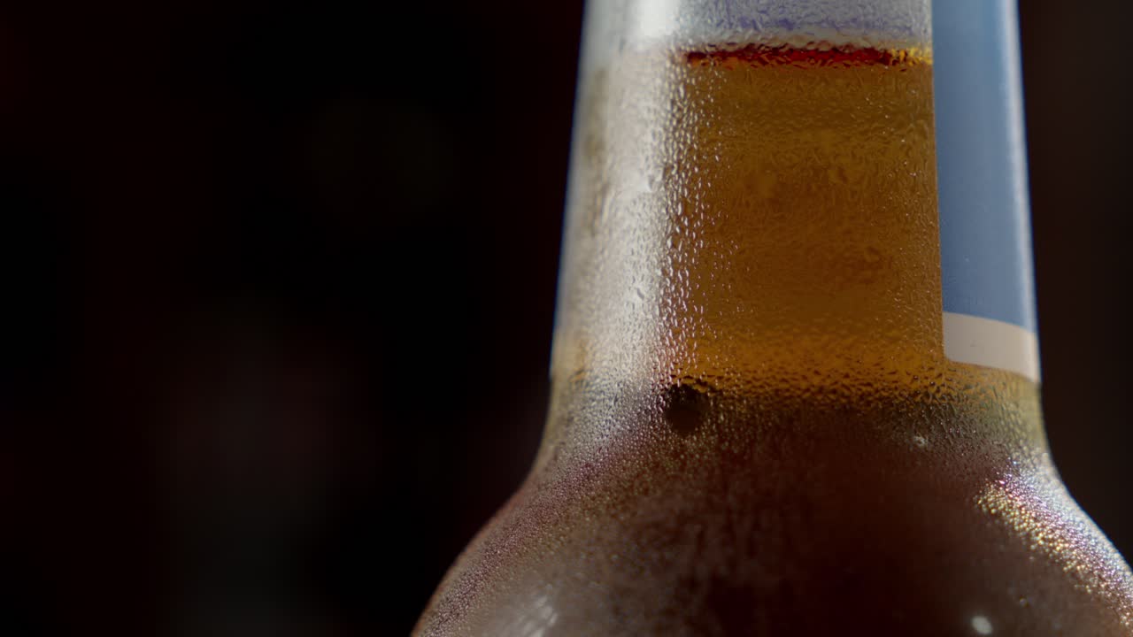 vista de cerca de la formación de condensación en el cuello de una cerveza recién vertida contra un fondo negro