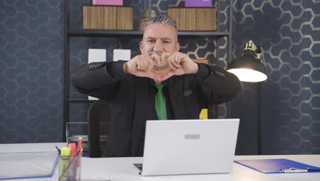 Loving-businessman-making-heart-symbol-at-camera.