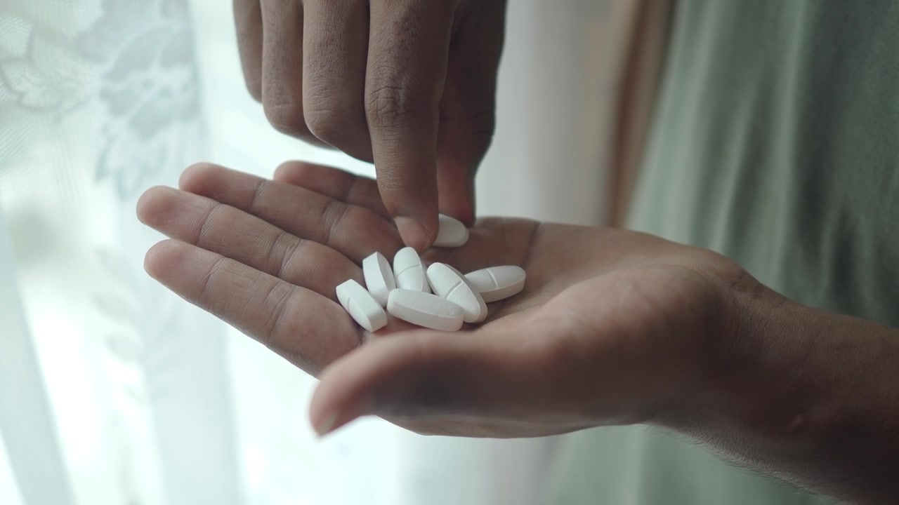 Persona che tiene pillole bianche nel palmo della mano