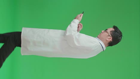 The Side View Of Asian Doctor With Stethoscope Wearing Glasses And White Coat Using Mobile Phone While Walking On Green Screen Chroma Key.