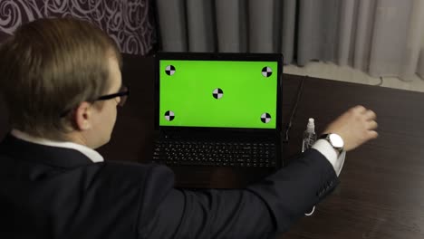 Man-removes-medical-mask,-takes-sanitizer-and-use-near-laptop-with-green-screen