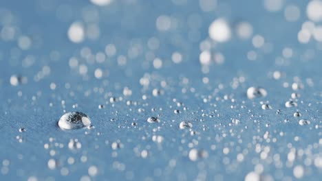 micro video of close up of water drops with copy space on blue background