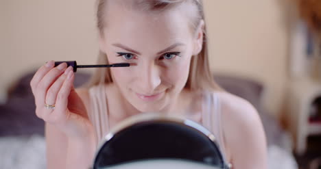 woman doing makeup painting eyelashes with mascara 3