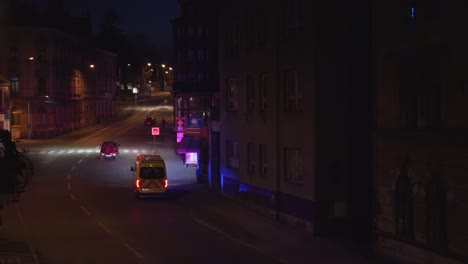 ambulance flashing lights on street at night, passing cars, covid pandemic