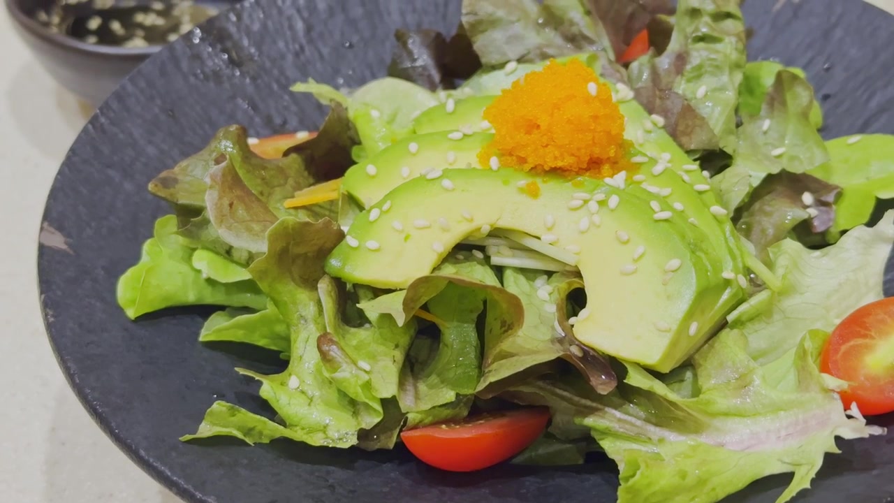 Nærbillede af en frisk avocadosalat i japansk stil, smukt anrettet med blandede grøntsager og traditionel japansk dressing. Sund og farverig salatpræsentation, der viser autentisk japansk madkultur.