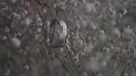 dolly shot of diamond and gold wedding rings placed on a bed of baby's breath
