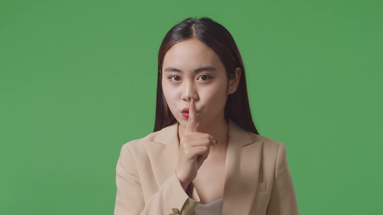 스튜디오의 녹색 스크린 배경에서 침 제스처를 보여주는 아시아 사업가의 클로즈업