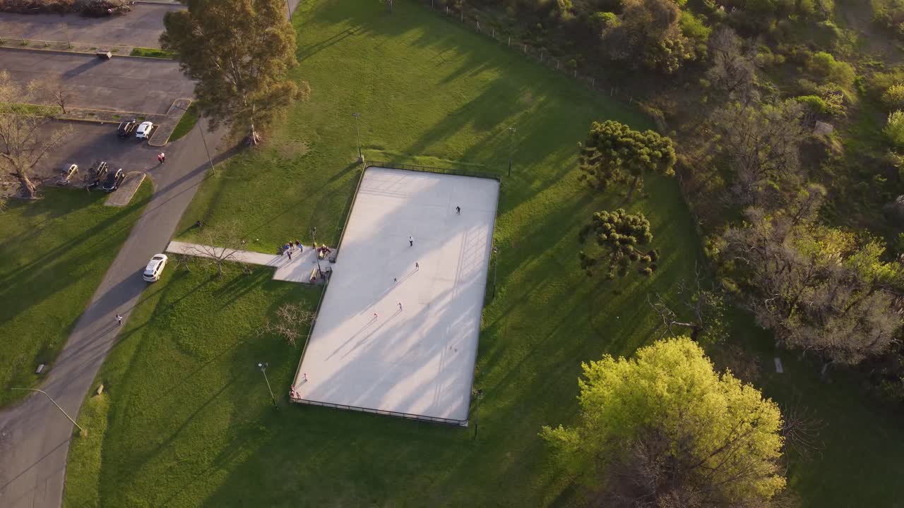 일몰 동안 스케이트 공원에서 흰색 바닥에서 스케이트를 타는 아이들의 공중 조감도, 4k