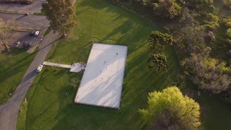 toma aérea de pájaros de niños patinando en suelo blanco en el parque de patinaje durante la puesta de sol, 4k