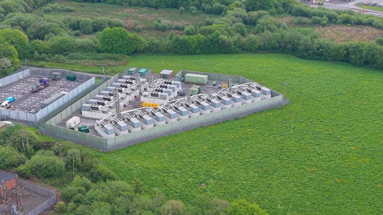 Rising Tilt Down Modern Gas Peaking Plant with exhaust stacks, generators, cooling systems. Facility provides rapid-response electricity to the grid during peak demand. Energy infrastructure. UK.