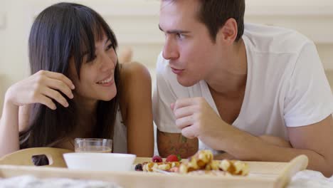 couple having fruit and waffle breakfast in bed