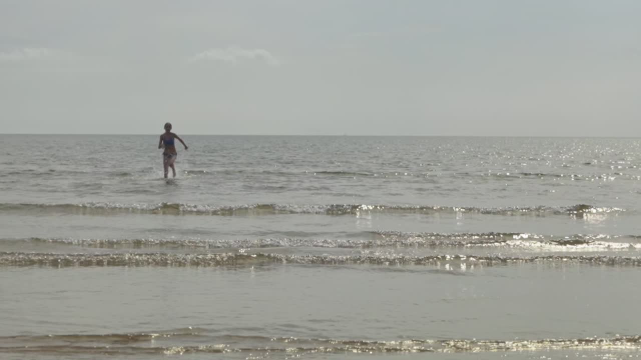 hermosa cámara lenta, salpicaduras, chica corriendo hacia la costa de la playa