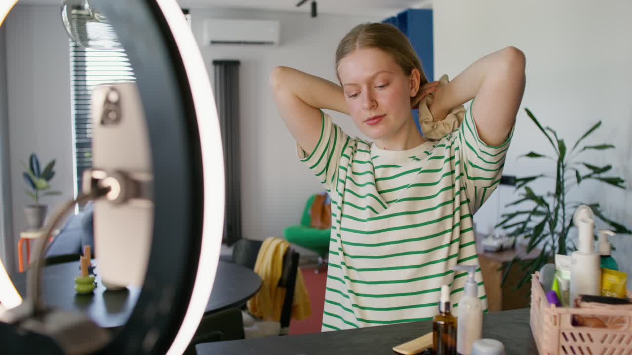 Giovane donna che si acconcia i capelli a casa