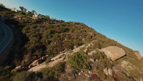 fpv drone follow motorcycle riding along topanga winding road, stunt tricks, california