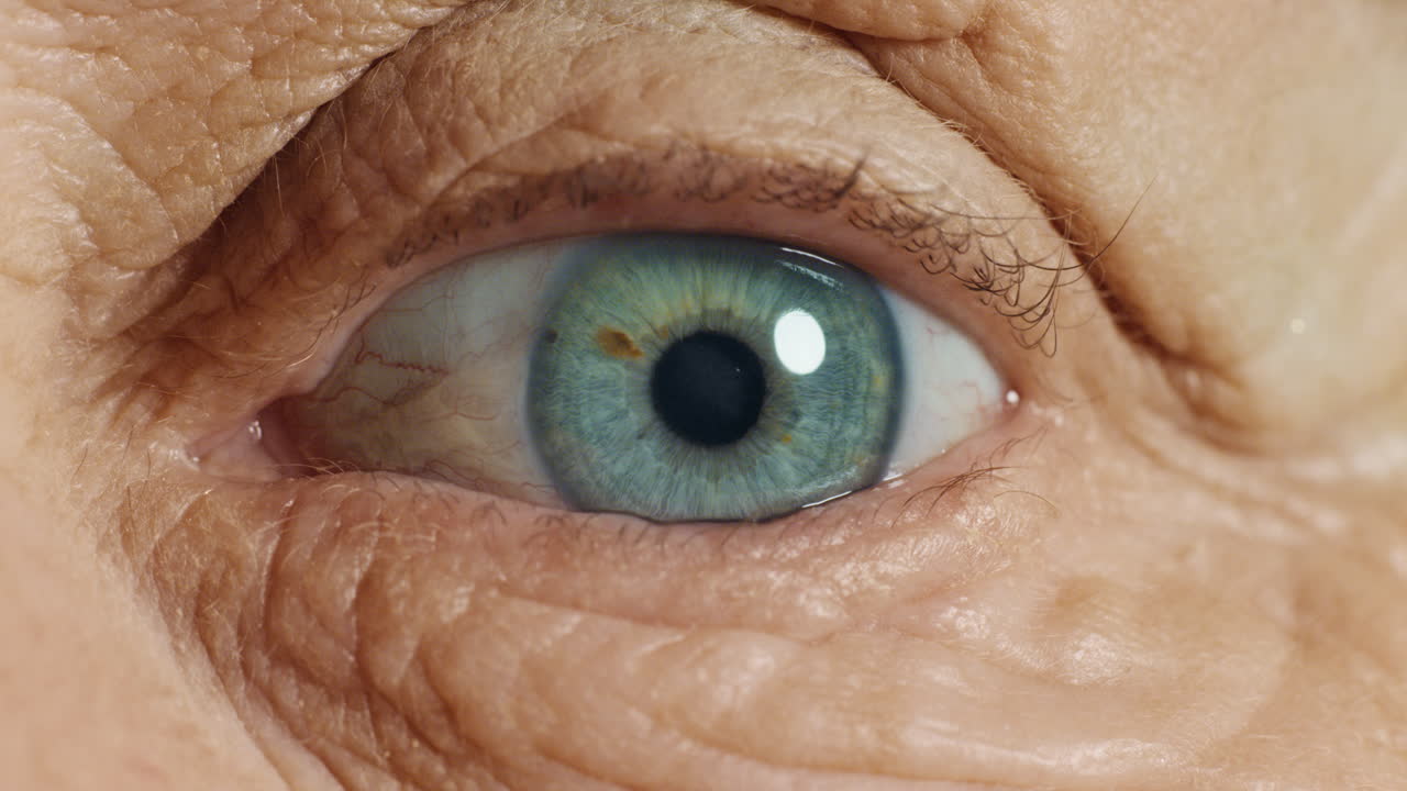 ojo azul de cerca abriéndose mujer vieja parpadeando macro envejecimiento belleza concepto de optometría