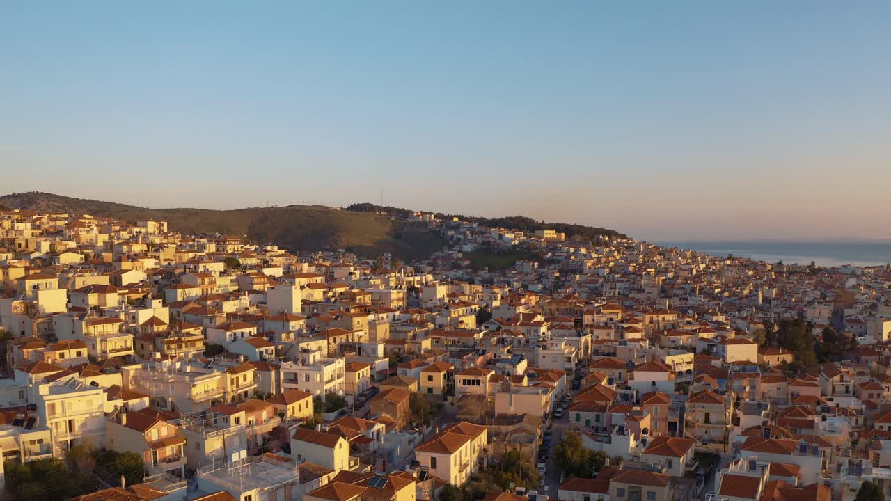 Volo di drone aereo all'alba sopra il centro di Mitilene che rivela in cerchio case sulle colline e montagne sul mare, Lesbo, Grecia.