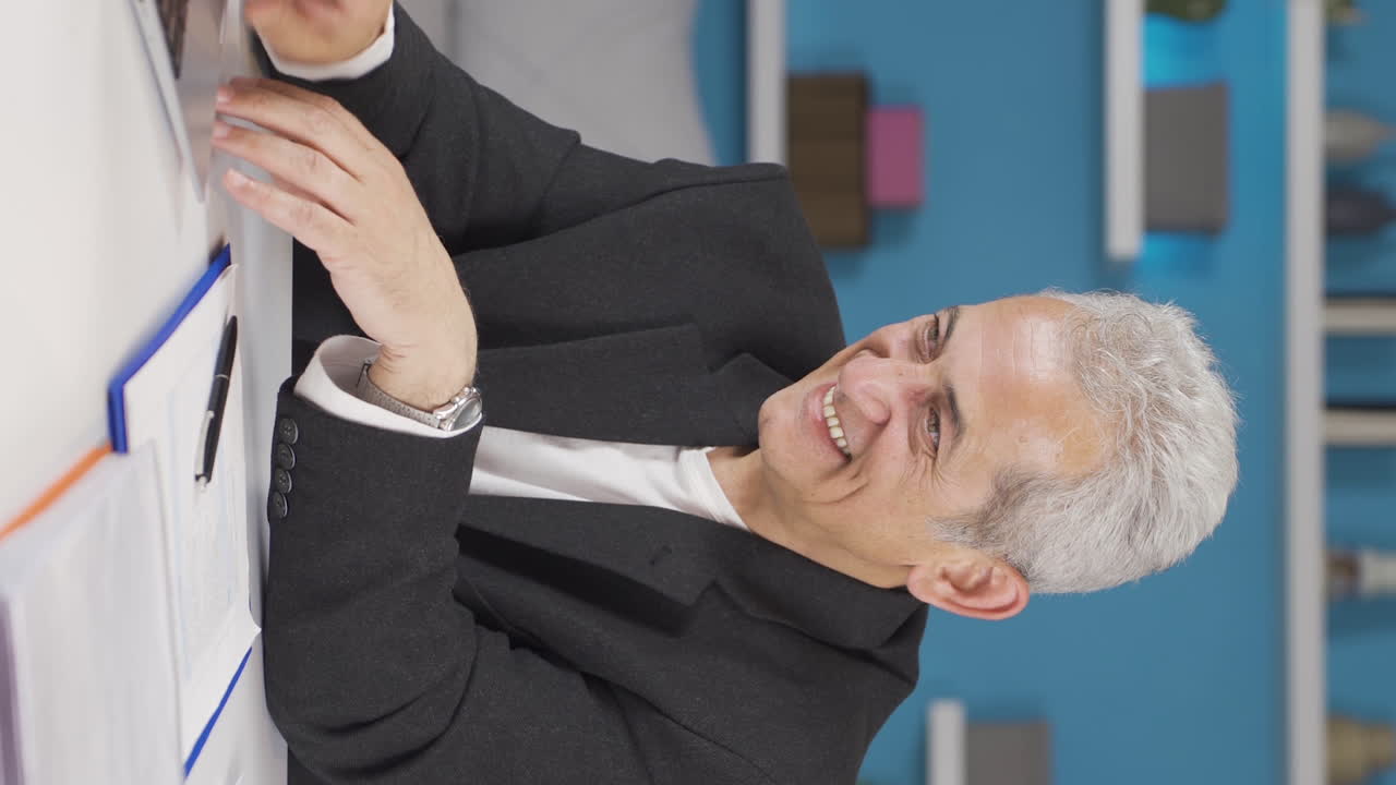video vertical de un trabajador de oficina en casa, hombre divertido trabajando en una computadora portátil, usándola.